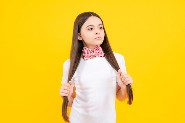 Conceito de infância Retrato de adolescente sorridente em camiseta com gravata borboleta isolada em fundo amarelo