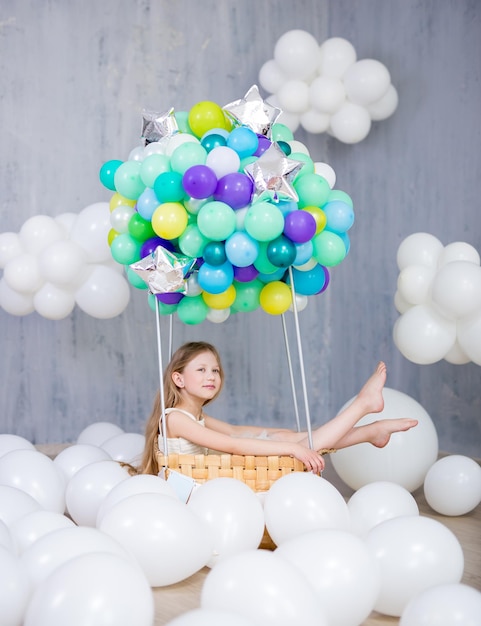 Conceito de infância, sonho e criatividade - menina feliz e fofa sentada em uma cesta de balão de ar