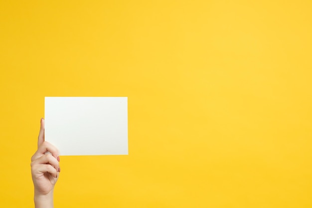 Conceito de informação Maquete de papel branco na mão da mulher Copie o espaço no fundo amarelo