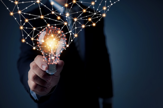 Conceito de inovação de ideia e tecnologia, empresário segurando uma lâmpada brilhando com a linha de conexão do poder