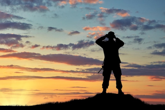 Conceito de inteligência. Silhueta de soldado olhando através de binóculos ao pôr do sol