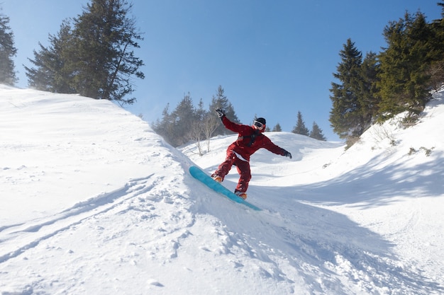 Conceito de inverno, lazer, esporte e pessoas - snowboarder ativo pulando nas montanhas em um dia ensolarado. close up de snowboard. estação de esqui sheregesh