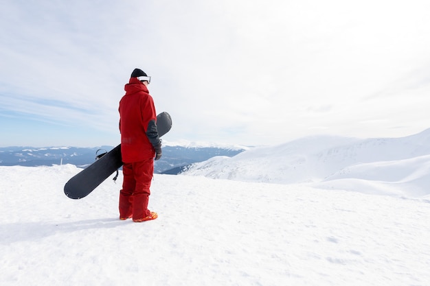 Conceito de inverno, lazer, esporte e pessoas - Snowboarder fica na encosta do sertão e segura o snowboard. Conceito de esqui
