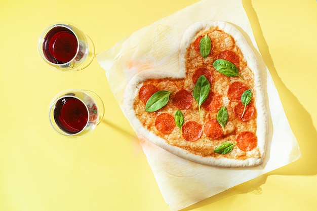 Conceito de jantar romântico a dois com vinho tinto e pizza em forma de coração. jantar para o dia dos namorados