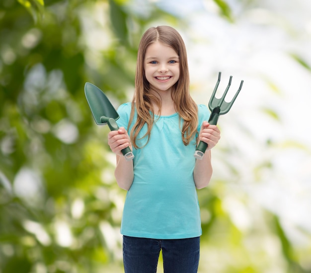 conceito de jardim e pessoas - menina sorridente com ancinho e colher