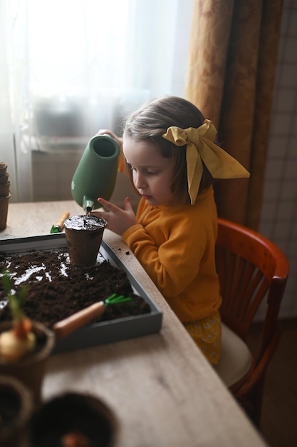 Foto conceito de jardinagem garotinha está envolvida em plantar sementes para mudas derramando terra em vasos para cultivo