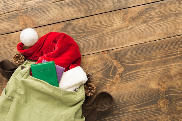 Conceito de jornada de Natal. Mochila com chapéu de Papai Noel e passaportes na mesa de madeira Vista superior