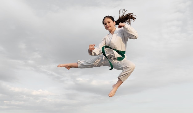 Conceito de judô menina adolescente praticando judo menina lutadora de judo salta no fundo do céu