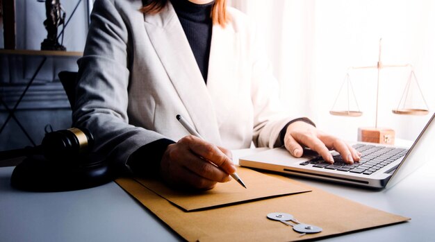 Conceito de justiça e direito Juiz masculino em um tribunal com o martelo trabalhando com computador e óculos de teclado de encaixe na mesa na luz da manhã