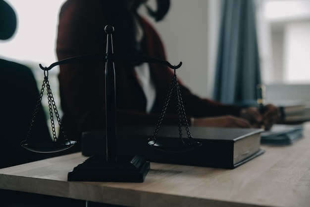 Conceito de justiça e direito Juiz masculino em uma sala de julgamento com o martelo trabalhando com computador e acoplando óculos de teclado na mesa na luz da manhã