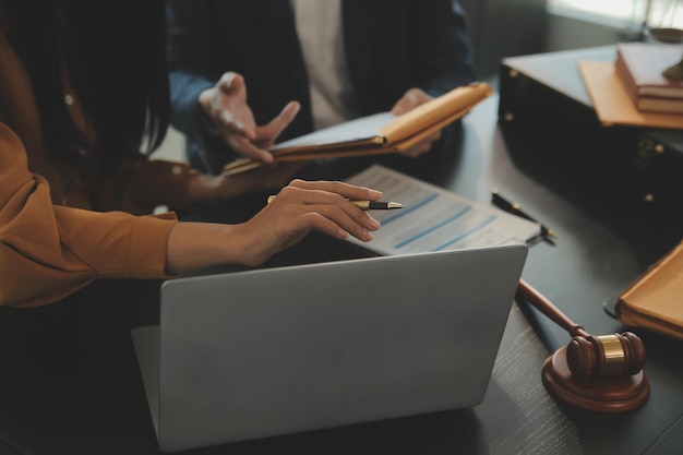 Conceito de Justiça e Direito O advogado apresenta ao cliente um contrato assinado com um martelo e uma reunião de equipe de direito ou jurídico no escritório de advocacia em segundo plano