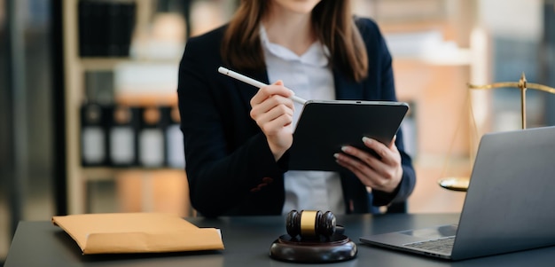 Conceito de justiça e lei Juiz masculino em um tribunal, o martelo trabalhando com smartphone, laptop e tablet digital na mesa de madeira