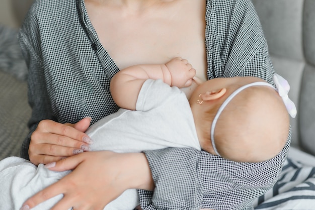 Conceito de lactação. Jovem mãe amamentando seu bebê recém-nascido em casa, close-up