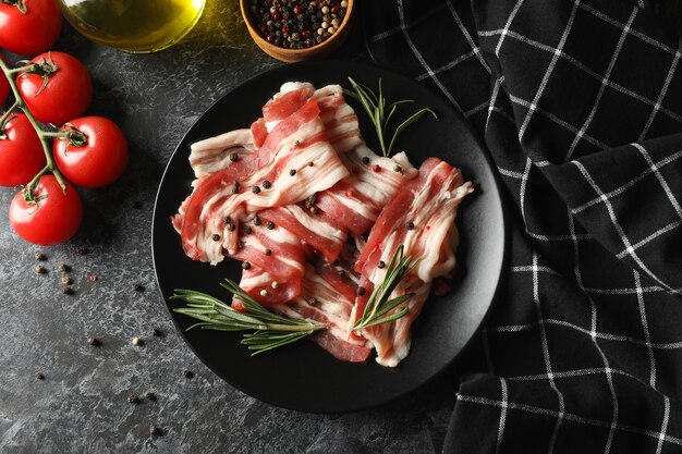 Conceito de lanche saboroso com prato de bacon em uma superfície preta esfumada