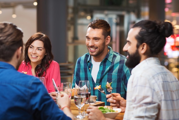 conceito de lazer, comida e bebida, pessoas e feriados - amigos felizes jantando no restaurante