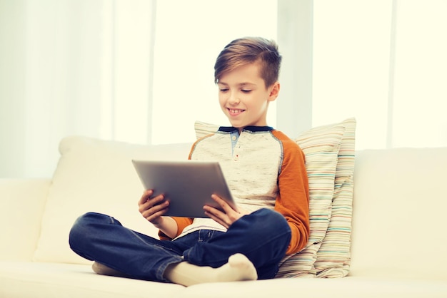 conceito de lazer, crianças, tecnologia e pessoas - menino sorridente com computador tablet pc em casa