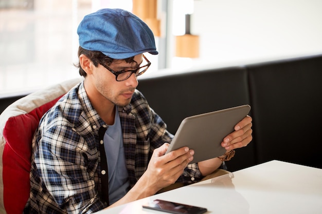 conceito de lazer, tecnologia, comunicação e pessoas - homem criativo com computador tablet sentado em uma mesa de café