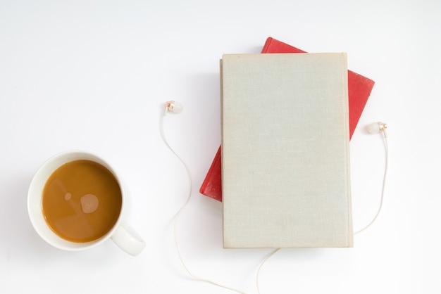 Conceito de livro de áudio. fones de ouvido, café e livro de capa dura sobre a mesa.