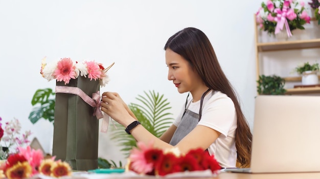 Conceito de loja de flores Florista feminina fazendo buquê de flores coloridas e gravata com laço na sacola de compras
