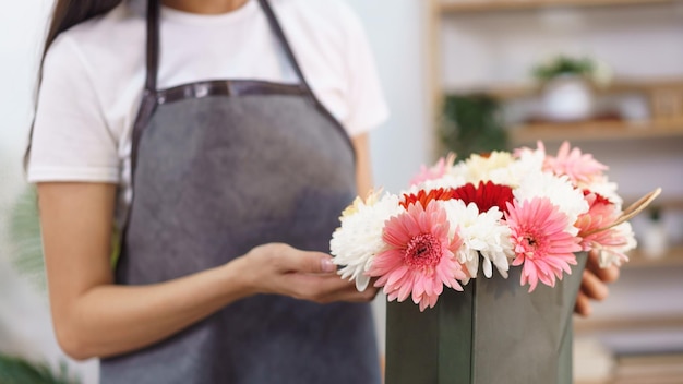 Conceito de loja de flores Florista feminina fazendo buquê de flores de crisântemo e gerbera na sacola de compras