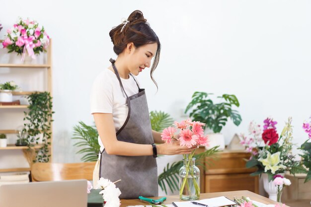 Conceito de loja de flores Florista feminina organiza gerbera rosa e flor colorida em vaso com felicidade