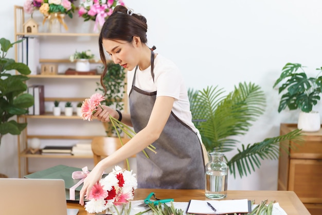Conceito de loja de flores Florista feminina pega gerbera colorida na sacola de compras para organizar em vaso