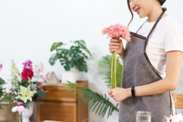 Conceito de loja de flores Florista feminina segura gerbera rosa na mão para se preparar para fazer buquê de flores