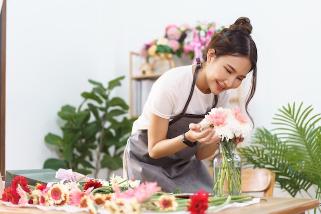 Conceito de loja de flores Florista feminina sorrindo e cheirando a flores coloridas em um vaso com felicidade