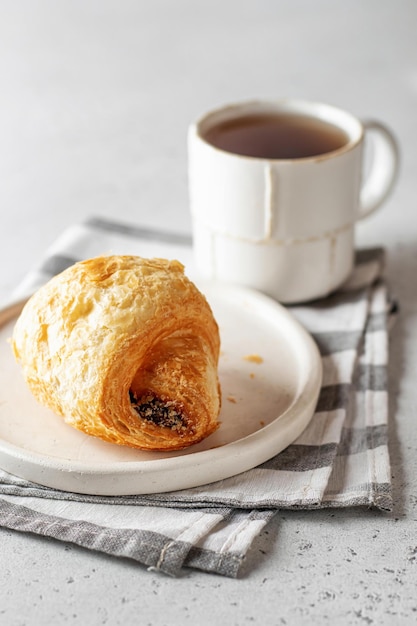 Conceito de manhã Croissant fresco na chapa branca em guardanapo com chá na luz de fundo