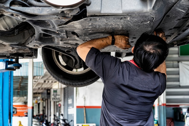 Conceito de manutenção de carro. Mecânico de automóveis, substituindo e derramando óleo fresco no motor na estação de serviço de manutenção. Técnico de reparo automático despeje o óleo do motor novo para substituir o antigo