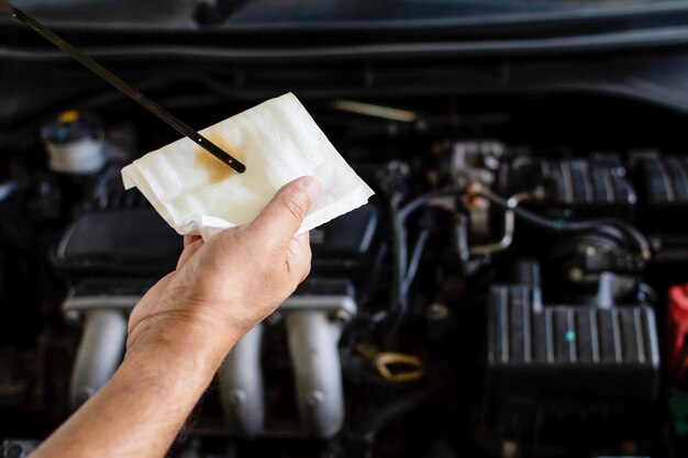 Foto conceito de manutenção do motor um técnico está verificando o nível do óleo do motor um homem segurando papel higiênico branco para limpar o óleo do motor