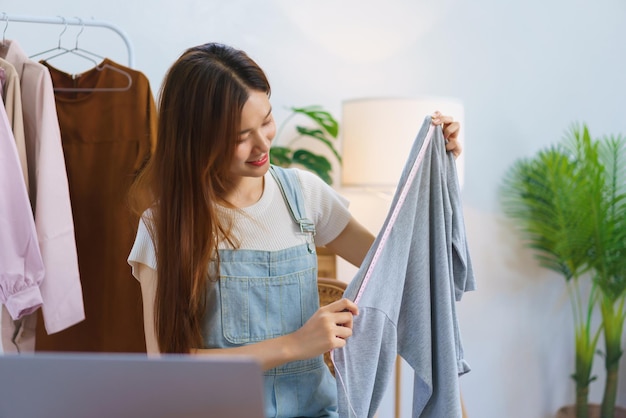 Conceito de marketing online Jovens mulheres asiáticas vendendo e apresentando detalhes de roupas em streaming de vídeo