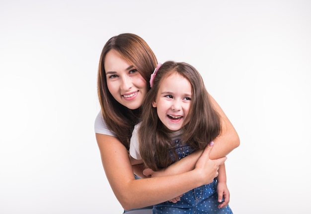 Conceito de maternidade, família e relacionamento - mãe feliz e filha se divertindo em branco