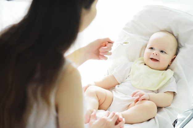 Conceito de maternidade. Uma jovem mãe alimenta seu bebê. Primeira isca e amamentação. Família numerosa com roupas brancas.