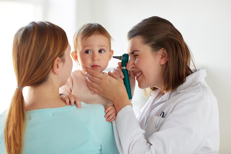 Foto conceito de medicina, cuidados de saúde, pediatria e pessoas - otorrinolaringologista ou médico examinando a orelha do bebê com otoscópio e mulher jovem na clínica