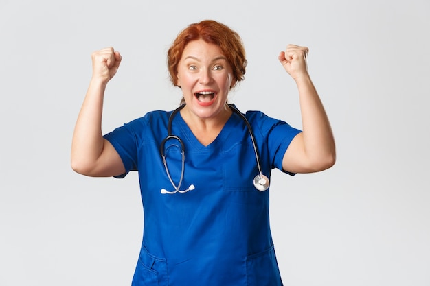 Foto conceito de medicina, saúde e coronavírus. trabalhador médico empolgado e emocionado, regozijando-se com o evento bem-sucedido, ergue o punho e diz hooray, sim gesticule, ganhando ou celebrando boas notícias