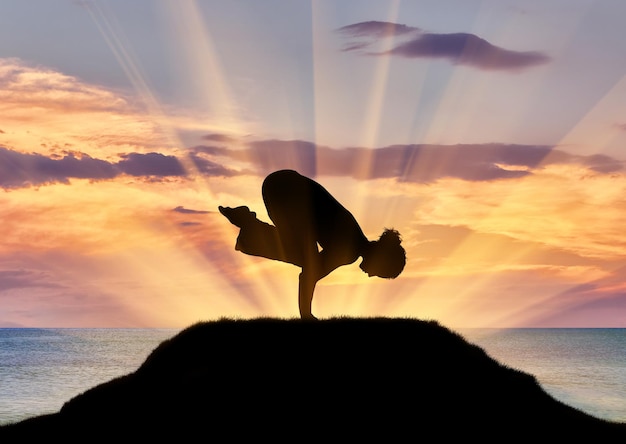 Conceito de meditação e relaxamento. Silhueta de uma garota praticando aula de ioga em um fundo de mar pôr do sol