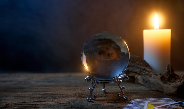 conceito de mesa de madeira de adivinhação e vela branca com uma bola de cristal e cartas de tarô