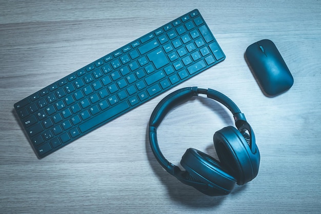 Conceito de mídia do espaço de trabalho Fones de ouvido sem fio pretos teclado e mouse na mesa de madeira