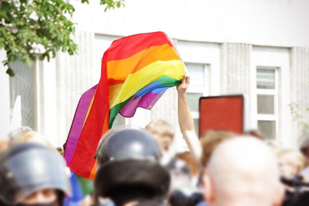 Conceito de minoria sexual Homem segurando a bandeira do arco-íris durante a parada gay ao ar livre