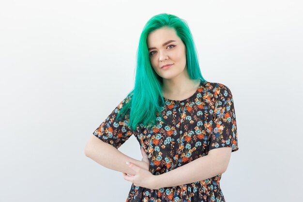 Conceito de moda, coloração de cabelo e pessoas - retrato de uma linda garota com cabelo verde em uma parede branca