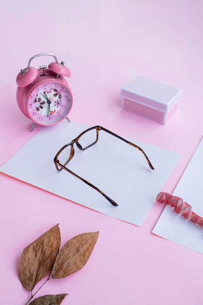 Conceito de moda e beleza deitado com acessórios femininos de óculos quadrados em fundo rosa