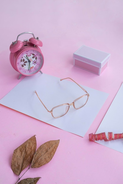 Conceito de moda e beleza deitado com acessórios femininos de óculos quadrados em fundo rosa