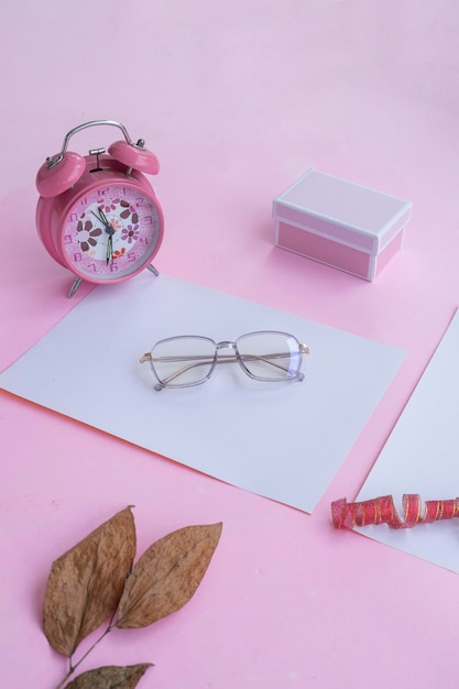 Conceito de moda e beleza deitado com acessórios femininos de óculos quadrados em fundo rosa