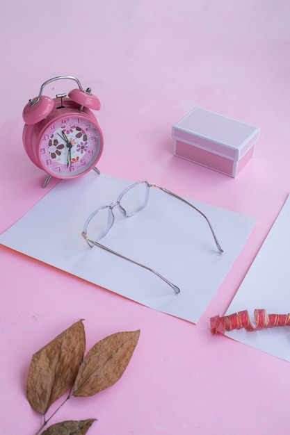 Conceito de moda e beleza deitado com acessórios femininos de óculos quadrados em fundo rosa