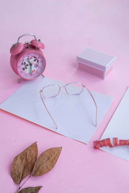 Conceito de moda e beleza deitado com acessórios femininos de óculos quadrados em fundo rosa