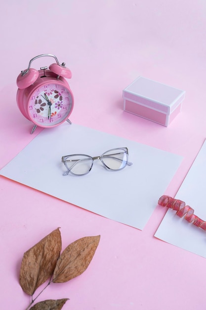 Conceito de moda e beleza deitado com acessórios femininos de óculos quadrados em fundo rosa