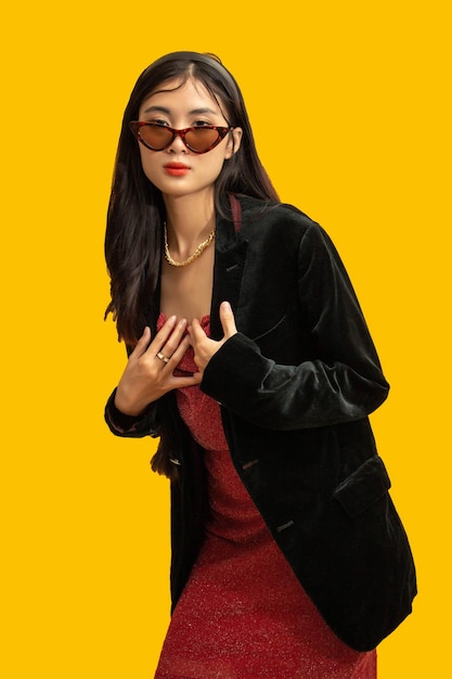 Conceito de moda Mulher na moda usa óculos escuros e vestido vermelho para posar com casaco preto grande