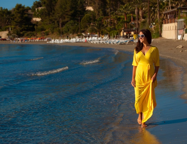 Conceito de moda Retrato de uma linda mulher com vestido longo amarelo em uma praia