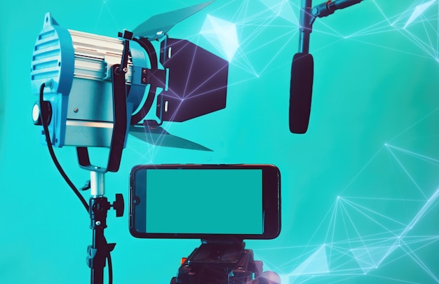 Foto conceito de multimídia de vídeo ao vivo com smartphone conectado microfone e refletores no fundo azul
